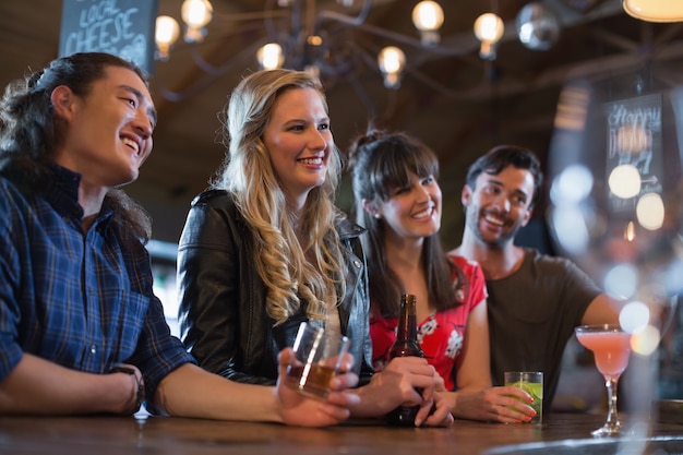 De glimlachende vrienden verzetten zich tegen wegkijken in de pub