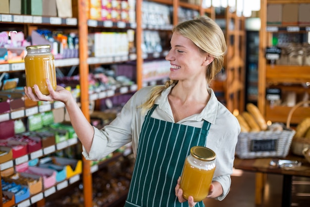 De glimlachende vrouwelijke kruiken van de personeelsholding honing in supermarkt