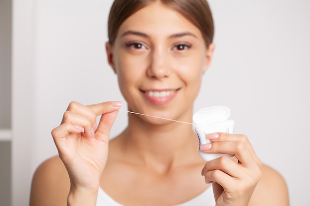 De glimlachende vrouwen gebruiken tandzijde witte gezonde tanden