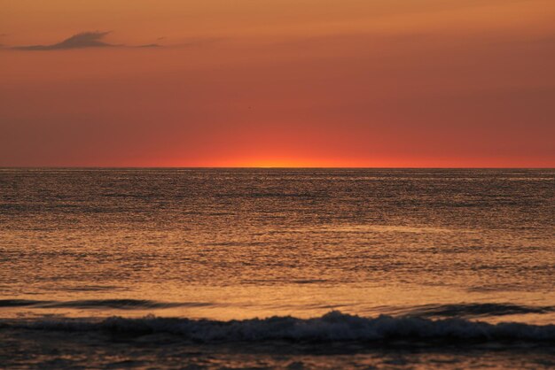 De gloeiende zon die aan de horizon van de zee of oceaan zinkt