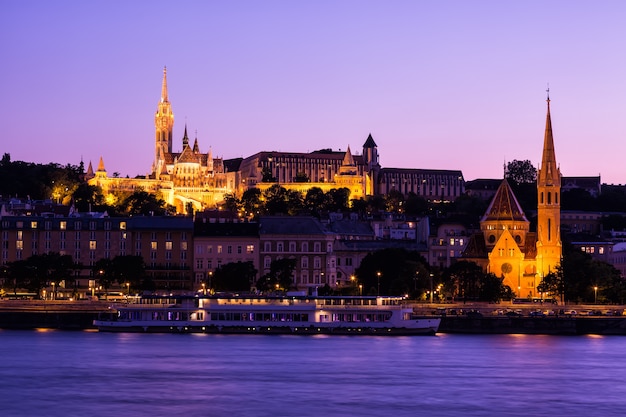 De gotische Matthias-kerk, in het Buda-district dichtbij het Fisherman's Bastion bij zonsondergang met sightseeingschip