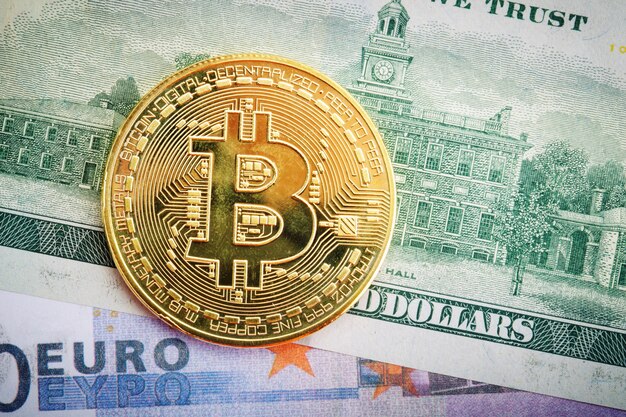 De gouden munt van bitcoin ligt op dollar en euro.