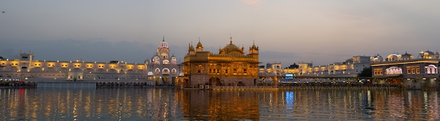 De gouden tempel in Amritsar, Punjab, India, de meest heilige icoon en eredienst van de Sikh-religie. Verlicht in de nacht, weerspiegeld op het meer.