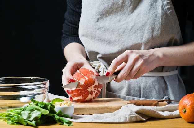 De grapefruitsalade van de vrouwenkok op een houten scherpe Raad.