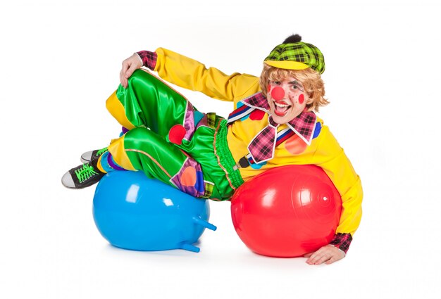 De grappige die clown ligt op ballen op wit worden geïsoleerd