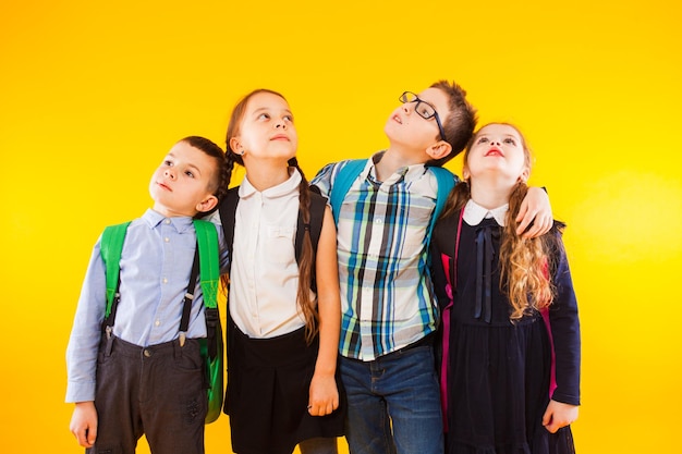 De groep basisschoolkinderen staat op een gele achtergrond en kijkt omhoog