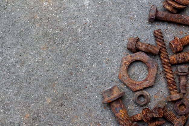 De groep noten en bouten van het huisvuil oude roestige staal stapelen zich op de stoffige cementvloer met selectieve nadruk en exemplaarruimte. Achtergrond voor mechanische of recycle en hergebruik concept