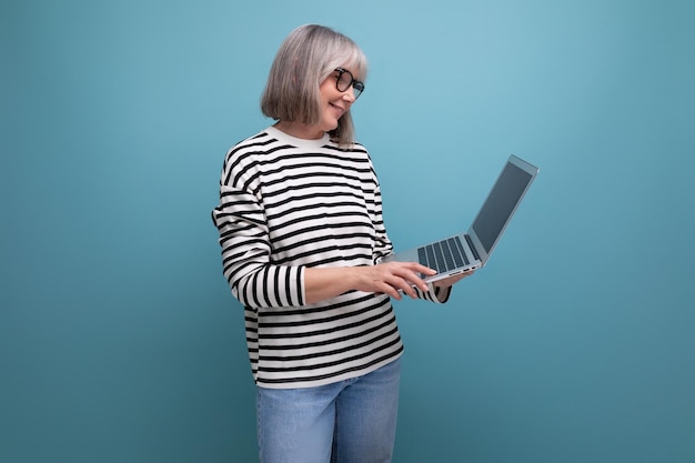 De grootmoeder van een succesvolle volwassen vrouw met grijs haar surft op internet met een laptop op helder