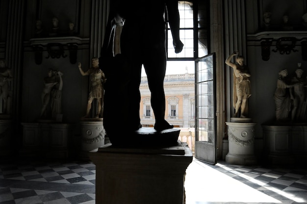 De grote centrale hal in het Capitolijnse Museum in Rome Het raam kijkt uit over de Campidoglio Het kolossale basanite beeld stelt de Baby Hercules voor en staat in het midden van de kamer Rome Italië
