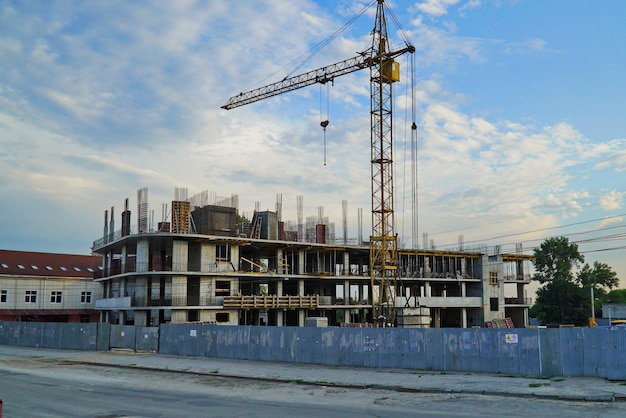 De grote torenkraan bij het bouwen van een winkelcentrum tegen de lucht