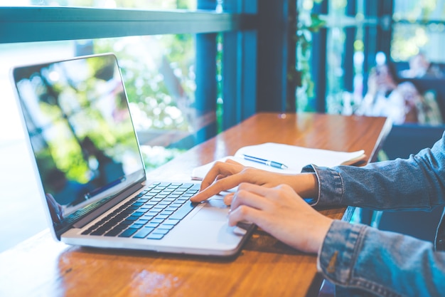 De hand die van de vrouw aan laptop in het bureau werkt