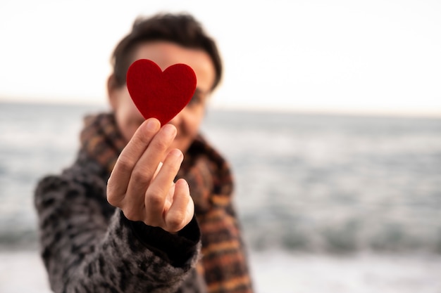 De hand die van de vrouw een rood hart op de kust houdt. concept van Valentijnsdag