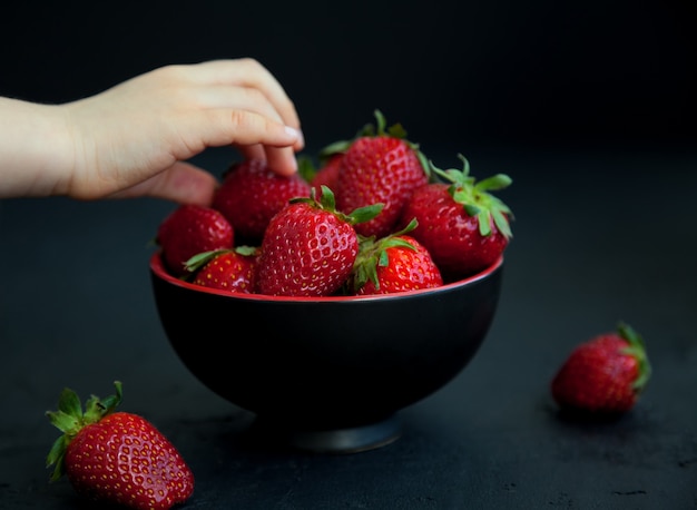 De hand die van het kind een aardbei neemt