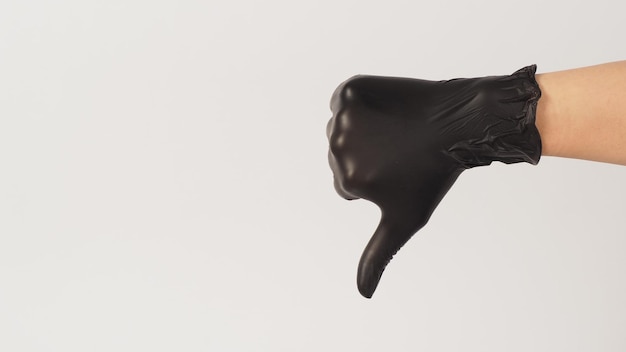 De hand draagt een zwarte latexhandschoen en houdt niet van of duim omlaag handteken op witte achtergrond