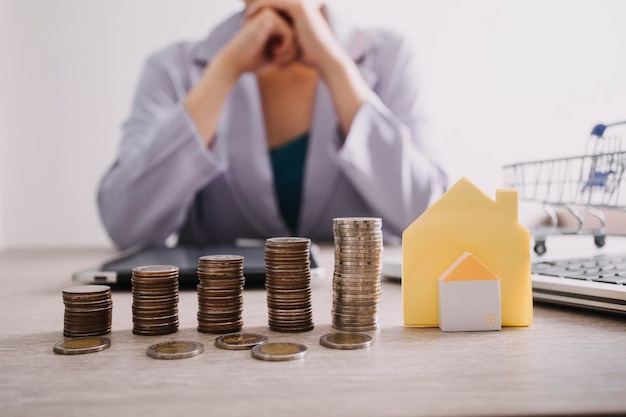 Foto de hand drukt rekenmachines spaarpot met houten huis koop of huur vraag op notitie met rekenmachines op bureau bespaar geld en koop huisconcept