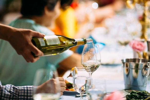 De hand gietende wijn van de kelner in een glas gediende lijst