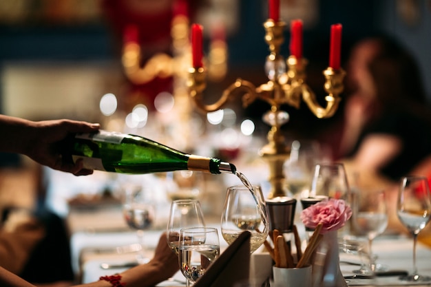 De hand gietende wijn van de kelner in een glas gediende lijst