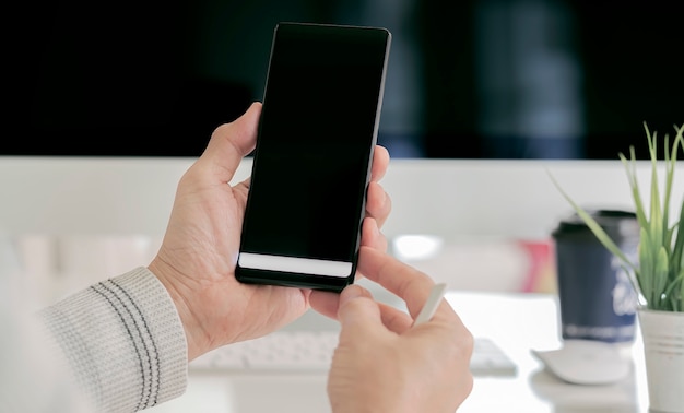 De hand holdng smartphone van de close-upmens met het zwarte scherm.