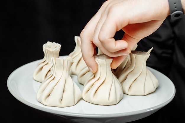 De hand houdt de chikali bij de staart Khinkali in een Georgisch restaurant in de hand Georgische keuken