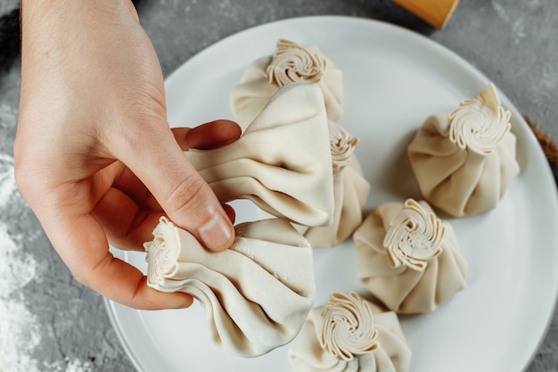 De hand houdt de chikali bij de staart vast. Khinkali in een Georgisch restaurant in de hand. Georgische keuken.