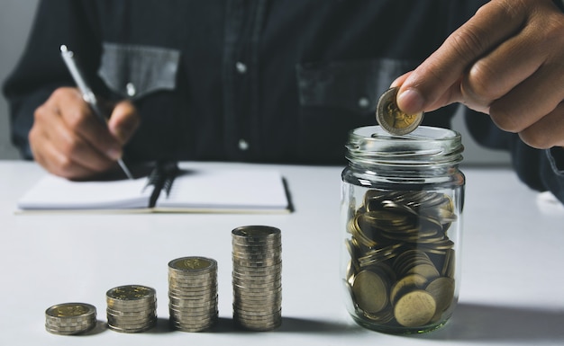 De hand laat vallen een muntstuk met de stapel van het geldmuntstuk het groeien voor zaken.