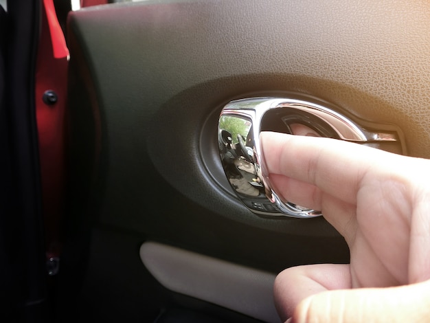 De hand opent de deurhendel in de auto.