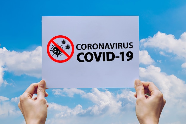 De hand toont holdingsdocument met coronavirus covid 19 van het woordvoorzichtigheid