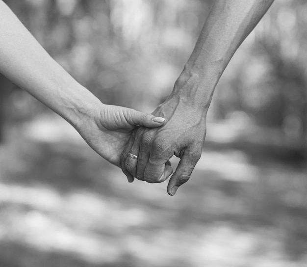 De hand van de man houdt de hand van de vrouw stevig vast Verliefde paar wandelen en hand in hand