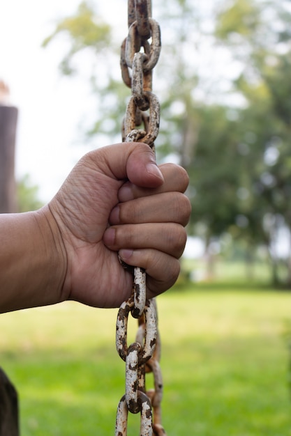 Foto de hand van de mens houdt op de oude roestketting