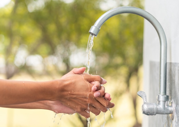 De hand van de mensenwas na het werken met openluchttapkraangootsteen, het schoonmakende concept van de hygiënebescherming