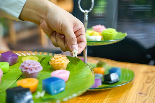 De hand van de Thaise chef-kok decoreert variëteiten traditionele kleurrijke Thaise desserts set stomende bloem zwarte vla kokosvla en dampende bonenlaag puddingcake