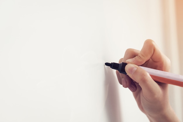 Foto de hand van de vrouw gebruikt een pen op een witte raad schrijft.