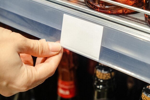 De hand van de vrouw geeft het prijsetiket in de winkel aan