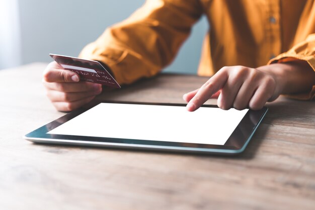 De hand van de vrouw houdt een creditcard vast en werkt bijna aan het bit. Online betalen voor online winkelen