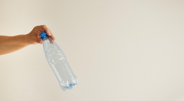 Foto de hand van de vrouw houdt een lege plastic fles vast