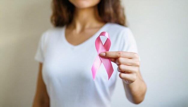 De hand van de vrouw houdt een roze lint vast dat het bewustzijn van borstkanker en medische zorg symboliseert