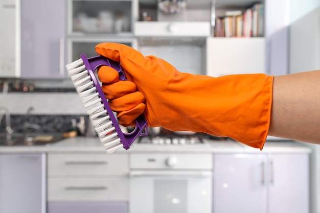 De hand van de vrouw in een beschermende handschoen met de borstel