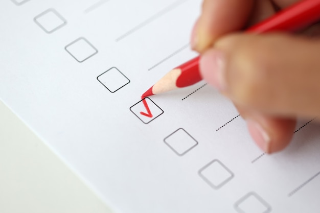 De hand van de vrouw markeert het antwoord met een rood vinkje in de test die het vragenlijstconcept doorstaat