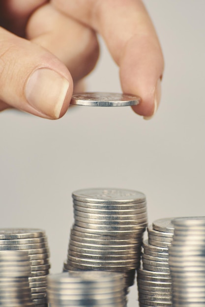 De hand van de vrouw zet zilveren geldmunten op een van de stapels concept van bedrijfsplanning en financiële kosten...