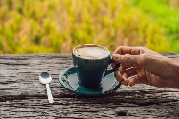 De hand van een man houdt een kopje koffie vast op de achtergrond van een oude houten tafel. Een hart voor koffie. St. Valentijnsdag concept.