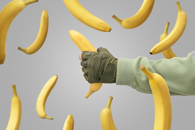 De hand van een man ving een vallende banaan op. Vallende bananen tegen een grijze achtergrond.