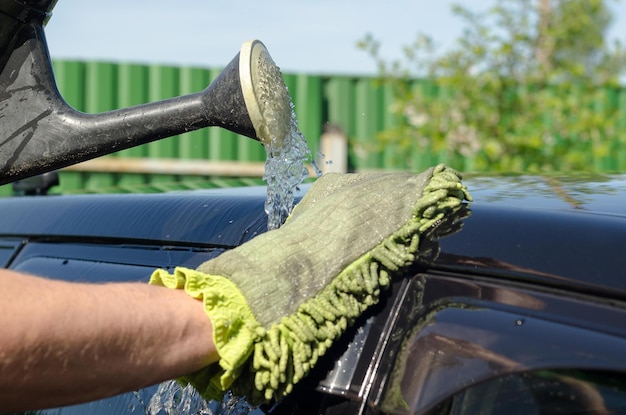 De hand van een man wast een auto met een vezeldoek