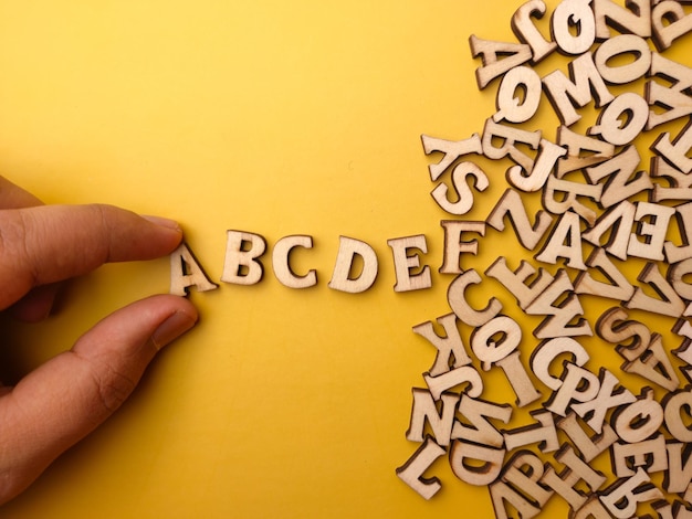 Foto de hand van een persoon rangschikt houten letters in de volgorde van abcde