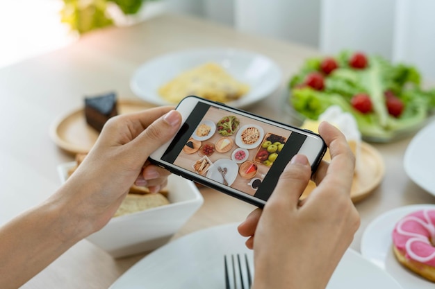 De hand van een recensent die een mobiele telefoon gebruikt om foto's te maken van eten aan de tafel van een restaurant Maak een foto om een recensie van het restaurant te schrijven en deze op internet te delen