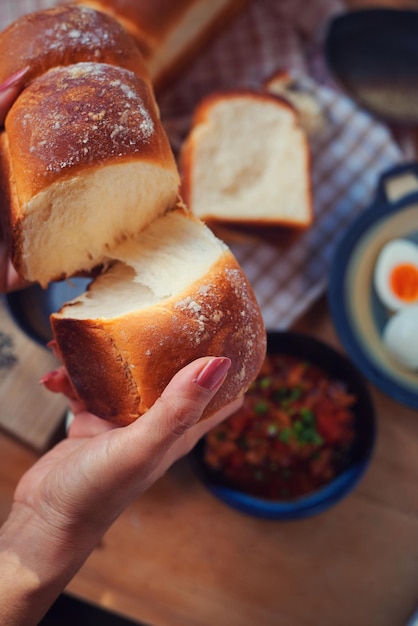 De hand van een vrouw houdt een brood vast.