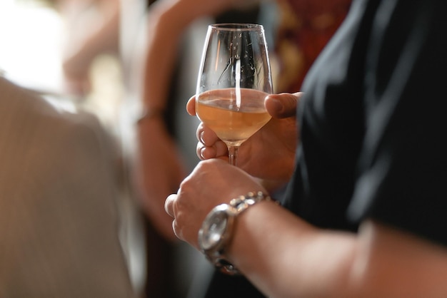 De hand van een vrouw houdt een glas champagne vast, een sprankelend drankje gegoten in een glas transparant glas een banket close-up een feest met vrienden