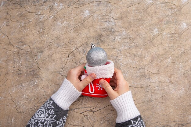 De hand van een vrouw houdt een rode kerstlaars en een zilveren kerstballon vast. Kerstmis en Nieuwjaar wenskaart concept. Vintage-stijl.