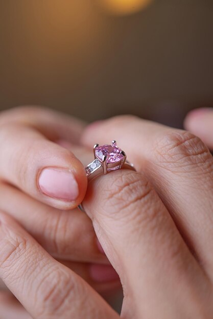 Foto de hand van een vrouw houdt een verlovingsring van roze saffier vast.