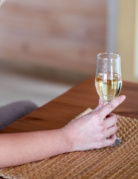 De hand van een vrouw houdt elegant een glas champagne of wijn vast