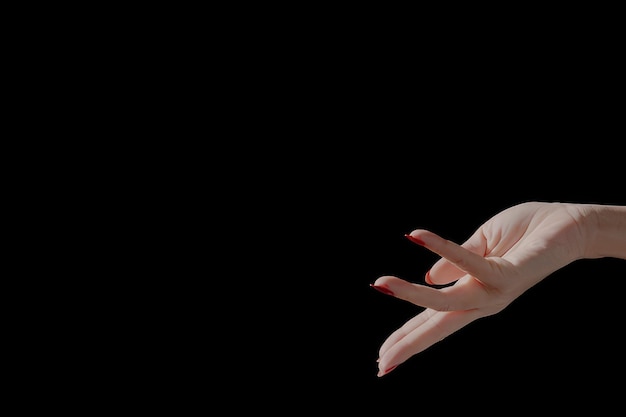 De hand van een vrouw met een rode manicure houdt haar vingers omhoog.